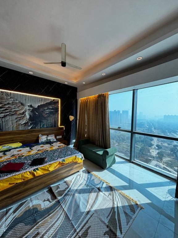 ein Schlafzimmer mit einem Bett und einem großen Fenster in der Unterkunft GAUR Luxury Stay in Ghaziabad