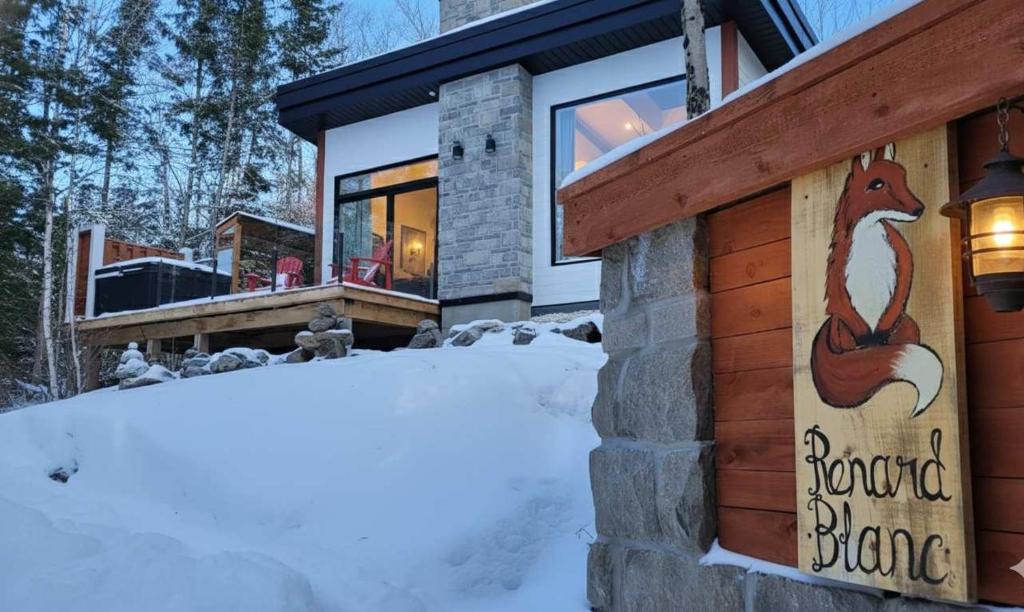 Le Renard Blanc - Spa and Incredible View في بلدية سان ألكسيس دي مونت: منزل في الثلج عليه لافتة سنجاب