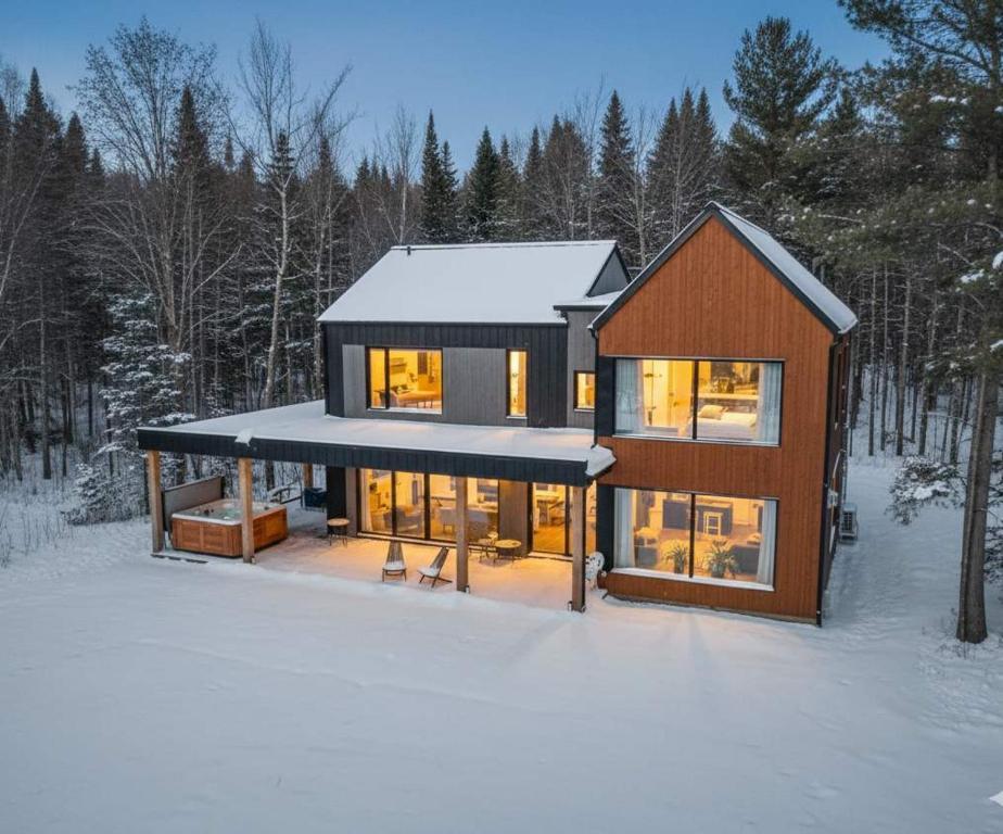 ein Haus im Schnee mit eingeschaltetem Licht in der Unterkunft Spa & River - Le Saint-Gabriel in Saint-Gabriel-De-Valcartier