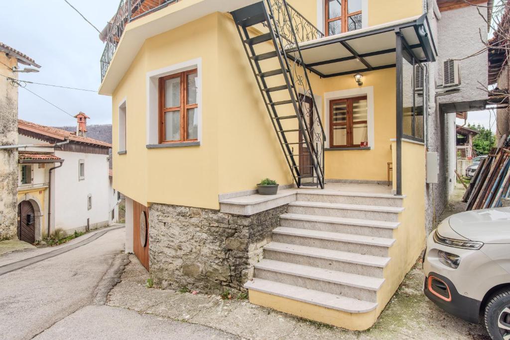 a yellow house with stairs on the side of it at Holiday Home Pr'Lukčevih with 4 Bedrooms & Sauna in Kanal