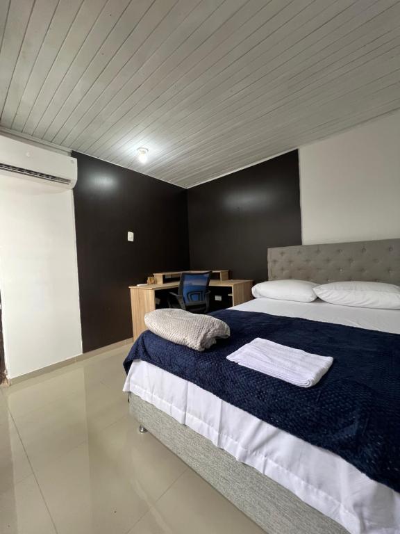 a bedroom with a bed with a blue blanket and a desk at Casa full Confort en el corazón de valledupar in Valledupar