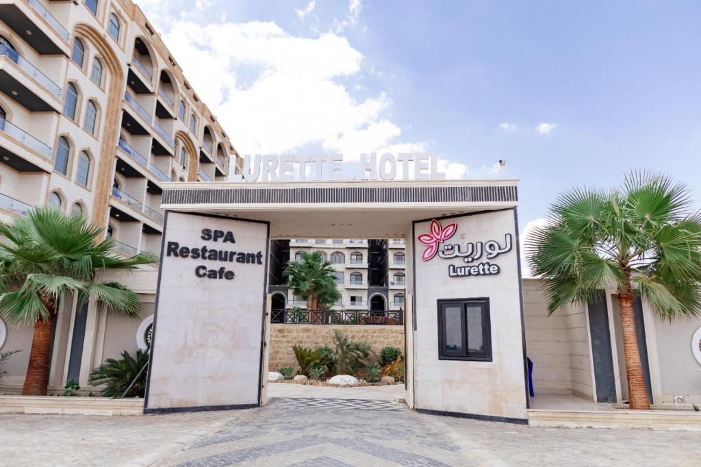a hotel entrance with palm trees in front of a building at فندق لوريت in Qaryat at Ta‘mīr as Siyāḩīyah