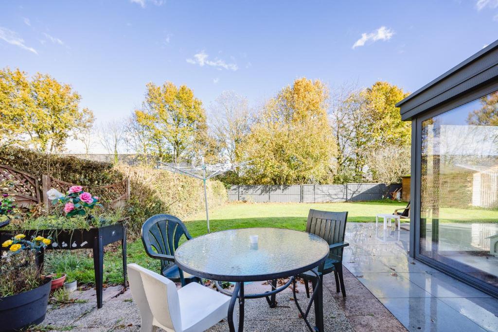 a patio with a glass table and chairs at Le Nid de Nouvoitou - Avec jardin in Nouvoitou