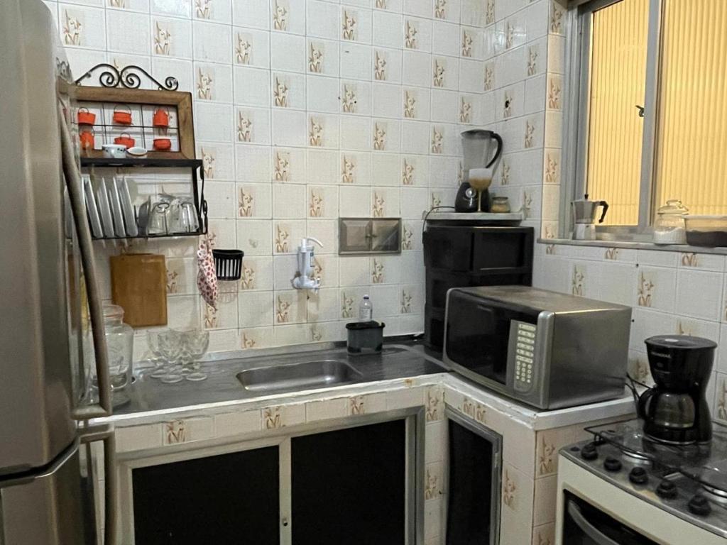 a kitchen with a sink and a microwave at Casa Laranja Hostel in Niterói