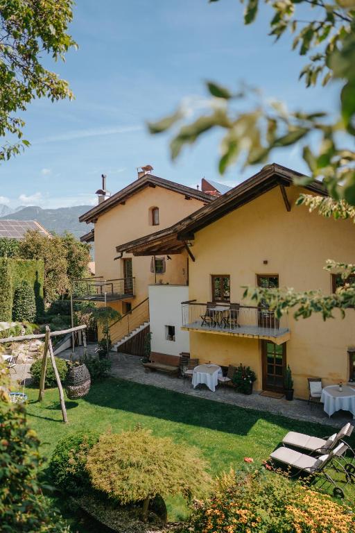 a house with a yard with chairs and tables at Ansitz Gurtenhof bei Meran, Apartments, Bett und bike Betrieb, eingezäunter Garten, Sauna, Eintritt ins Schwimmbad und Südtirol Pass in Tesimo