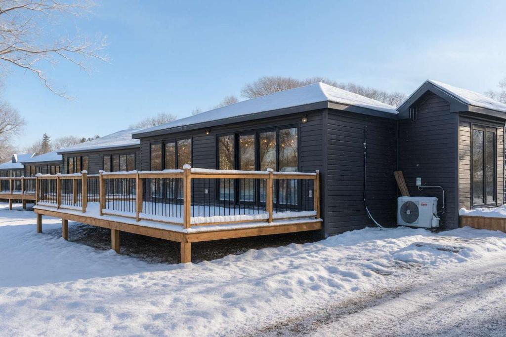 a black house with a deck in the snow at 2-bedroom Lake Front Cottage in Harwood ON #7 in Harwood