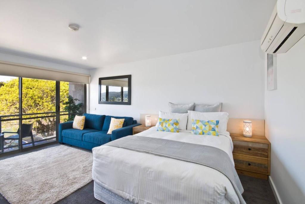 a bedroom with a large bed and a blue couch at Bay View - Ocean Nest in Lorne