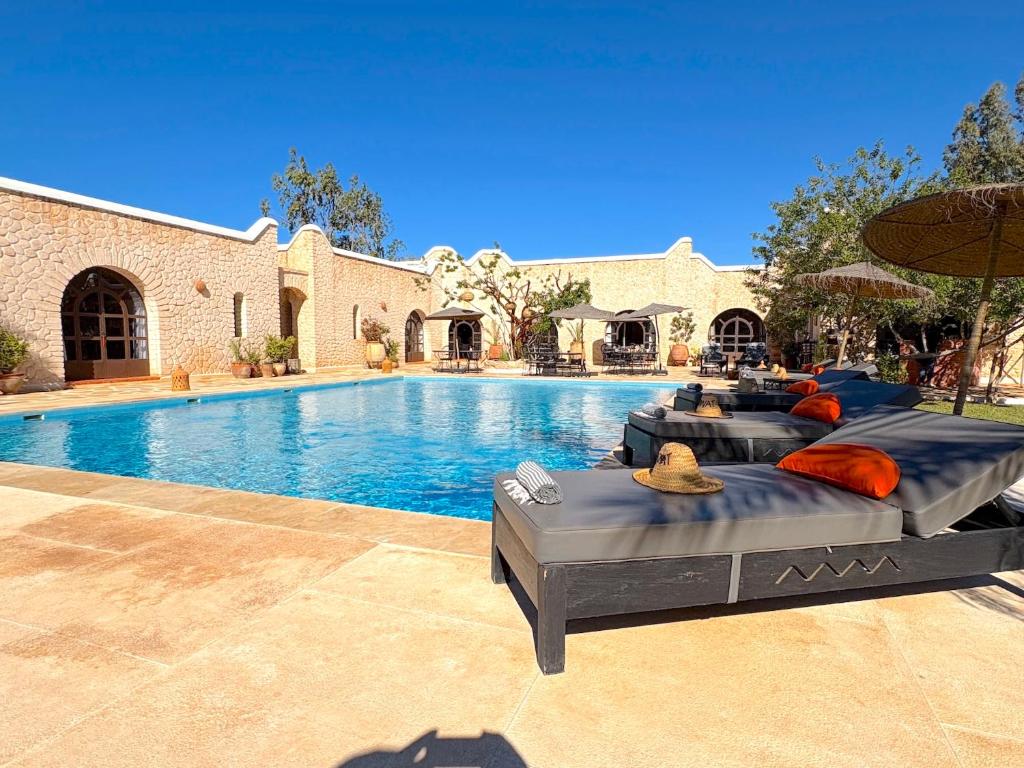 a swimming pool with a bed with pillows and an umbrella at Palais Tiyana in Al Ghar