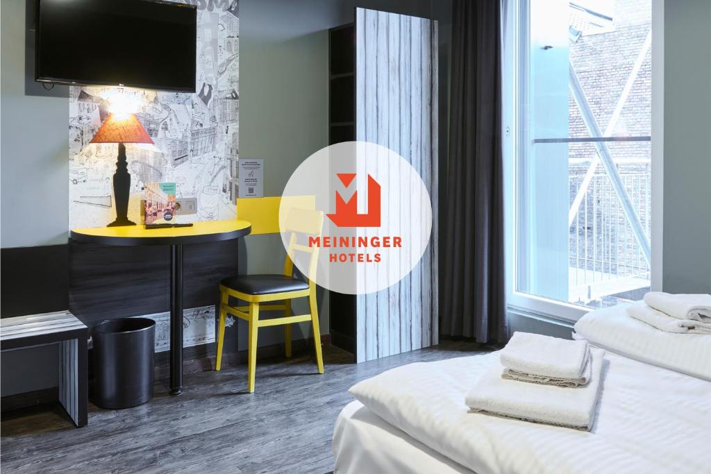 Una habitación de hotel con una cama y un escritorio con televisión. en MEININGER Hotels Bruxelles City Center, en Bruselas