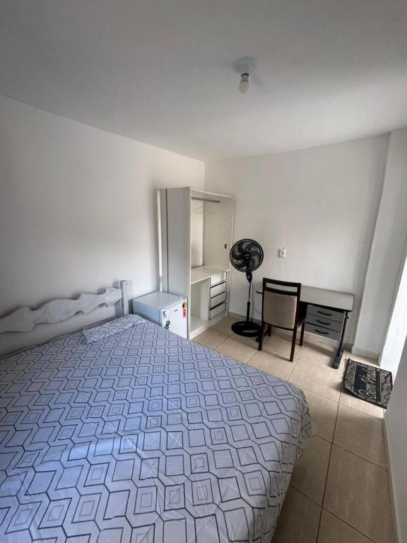 a white bedroom with a bed and a desk at Família Ebeneze in Nova Friburgo