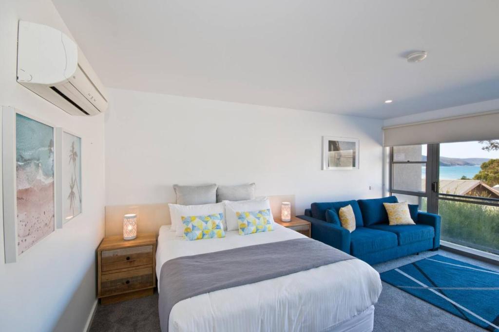 a bedroom with a bed and a blue couch at Bay View Ocean Views in Lorne