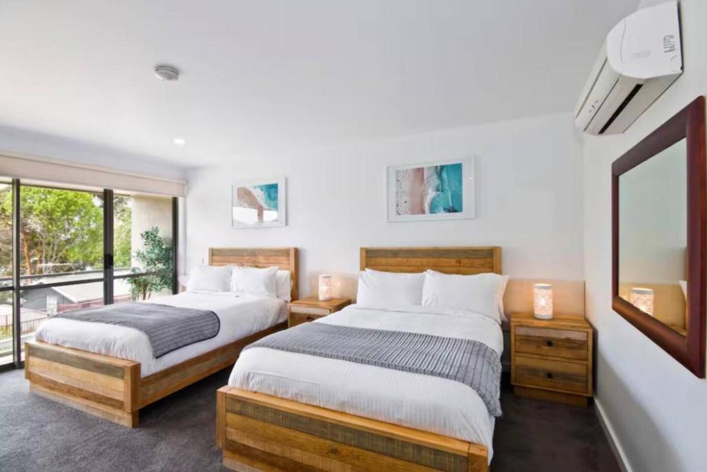 two beds in a room with a window at Bay View Ocean Breeze in Lorne