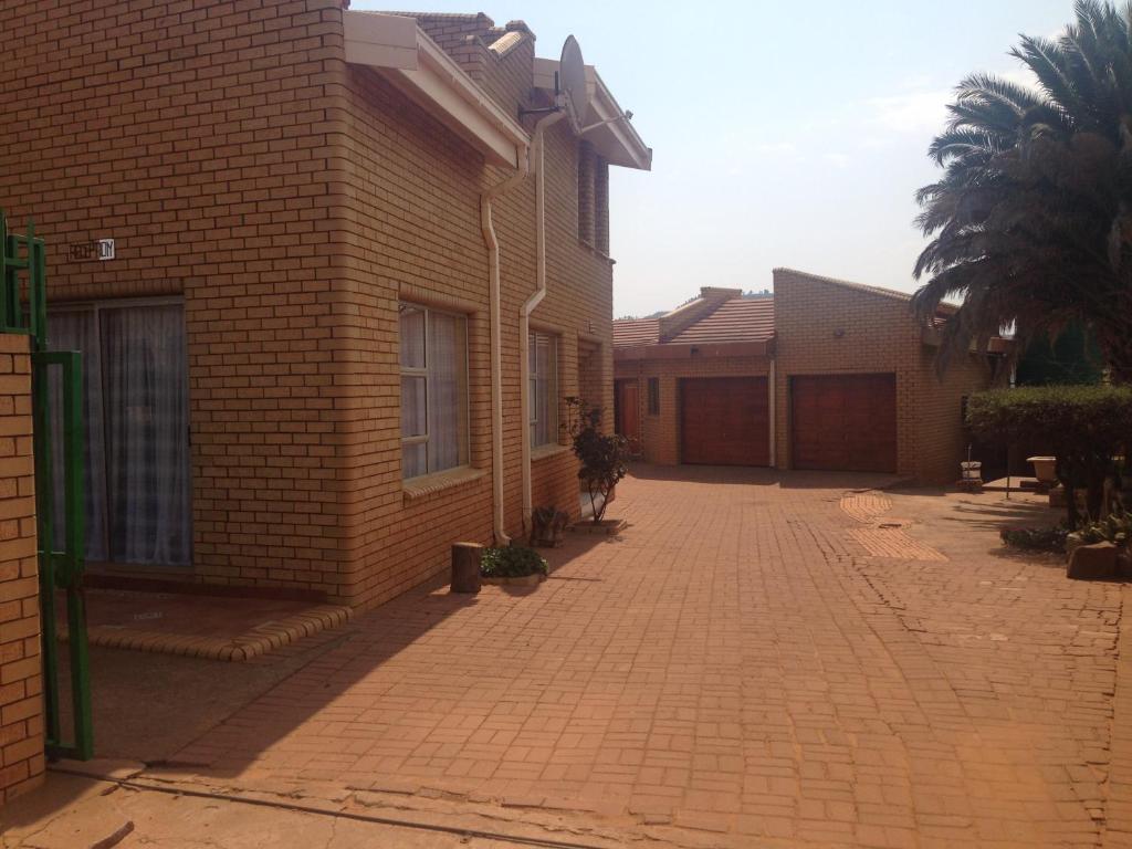 a brick alley between two buildings with a palm tree at Hae Bed and Breakfast in Leribe