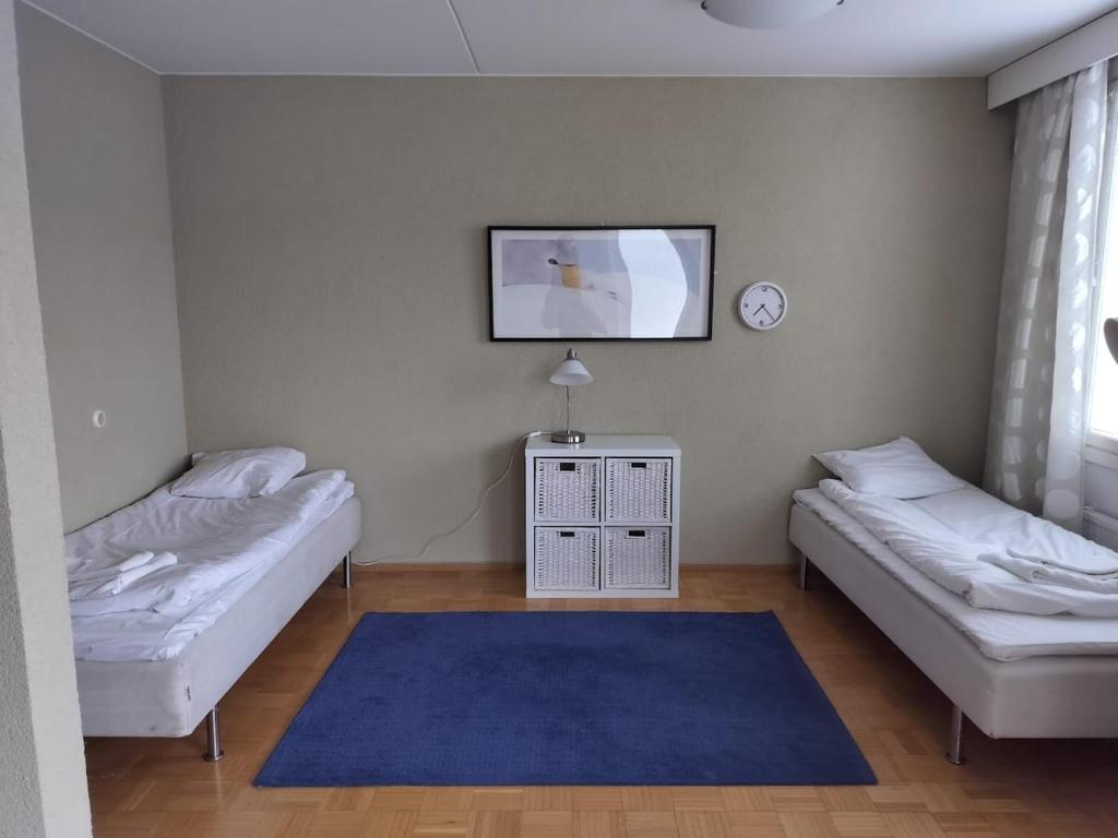 een kamer met twee bedden en een tv aan de muur bij Kotimaailma - Valoisa ja tilava neliö in Turku