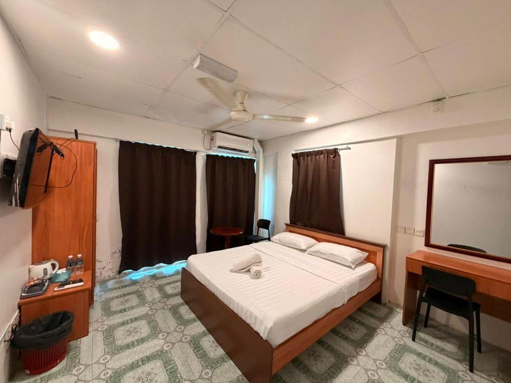 a bedroom with a bed and a flat screen tv at Hotel Western in Sandakan