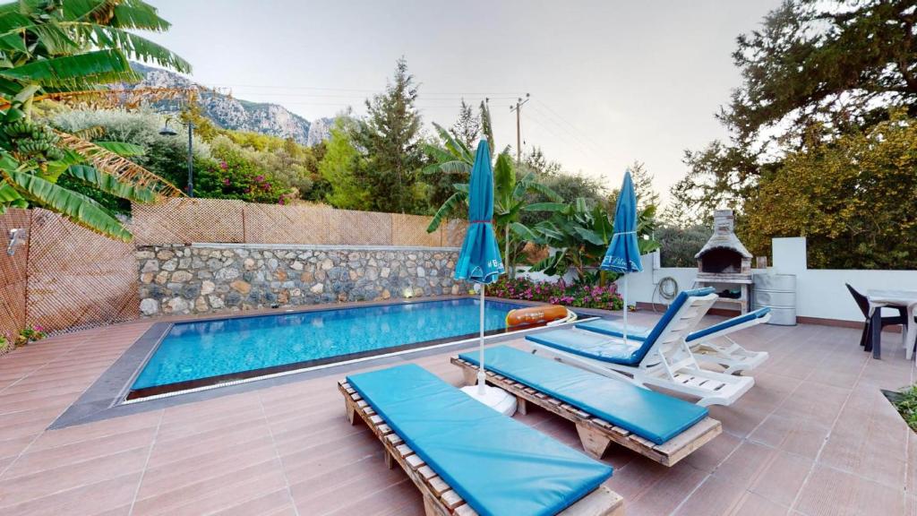 a swimming pool with two lounge chairs and umbrellas at Villa Cypress Villas in Kyrenia