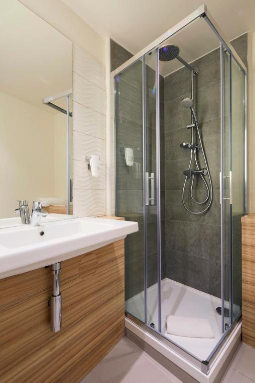 a bathroom with a shower with a sink and a toilet at Campanile Orléans Centre Gare in Orléans