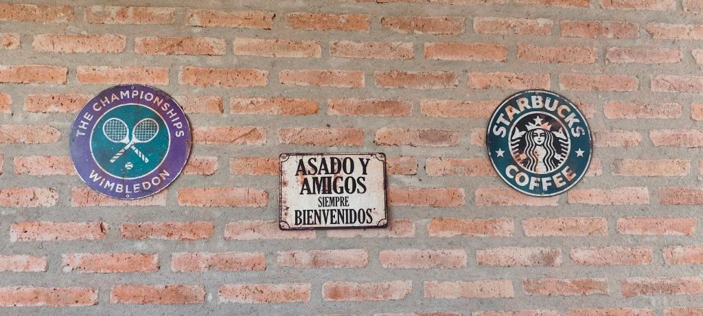 パソ・デ・ラ・パトリアにあるDIVINA CASITA PASO DE LA PATRIAのレンガの壁に3つの標識がある