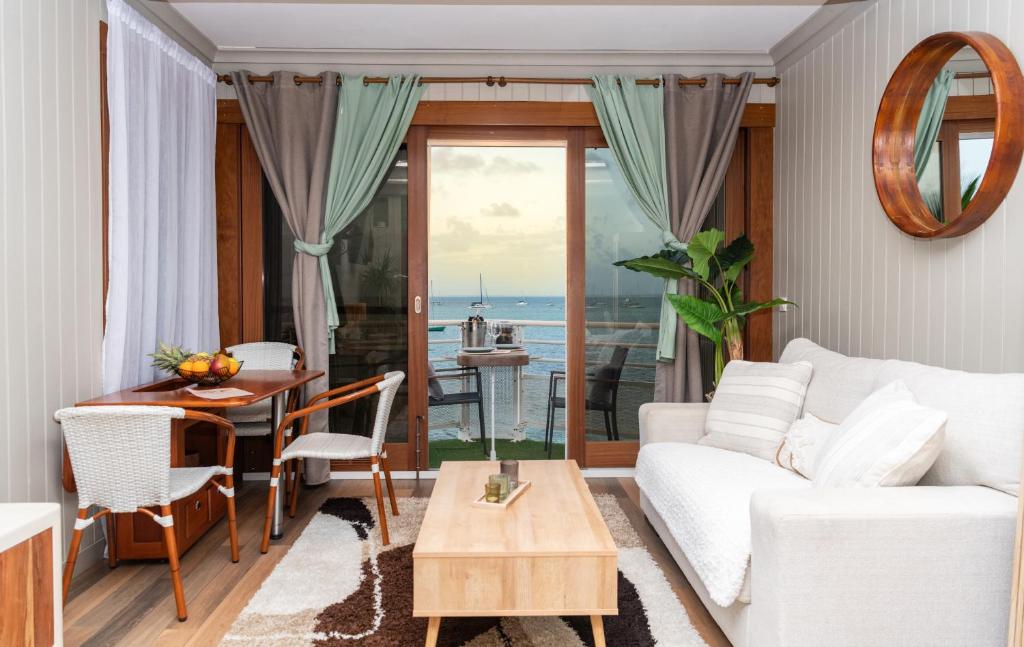 a living room with a white couch and a table at Cozy studio, beach and pool access with sea view in Marigot