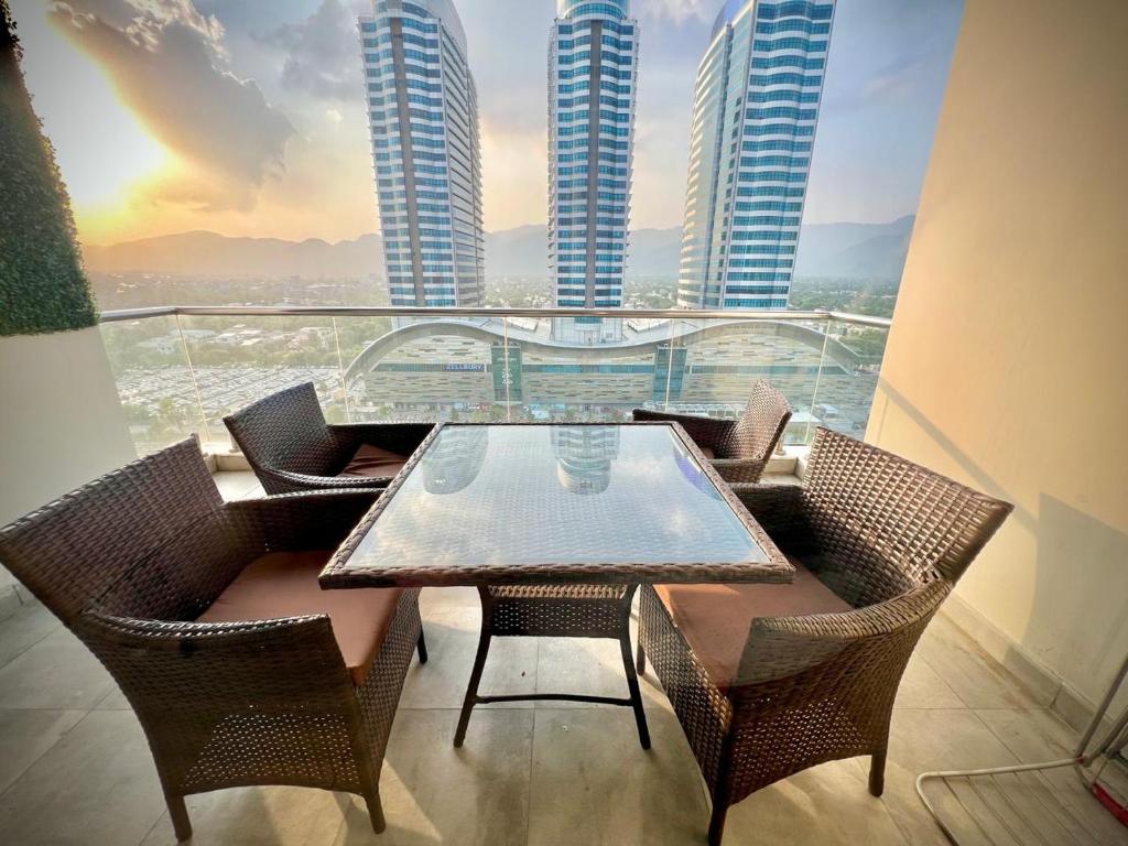 拉合尔Gold Crest Prime Heights Executive Apartments-DHA Lahore的阳台配有桌椅,享有建筑景致