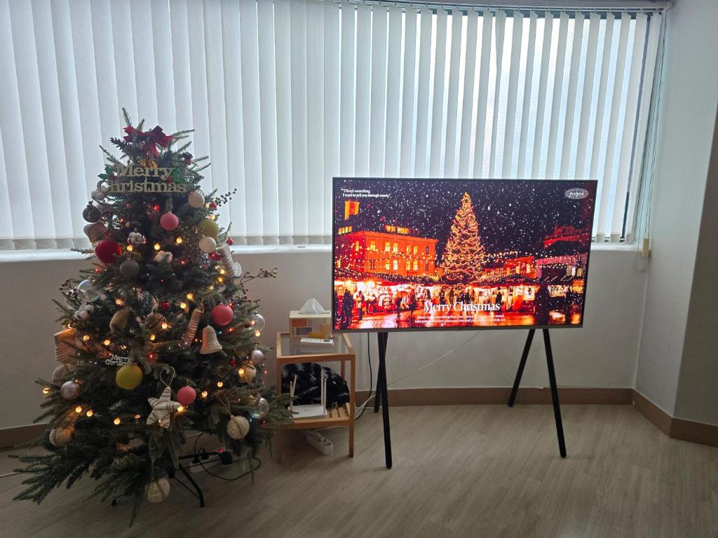 a christmas tree in a room with a painting at Haru Airport Stay Gimpo in Seoul