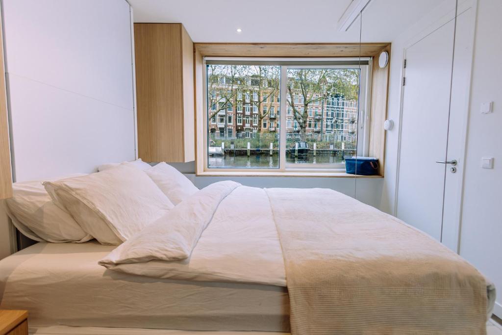 ein Bett in einem Zimmer mit Fenster in der Unterkunft The Amsterdam Houseboat Family - de Jordaan Brand New Houseboat! in Amsterdam