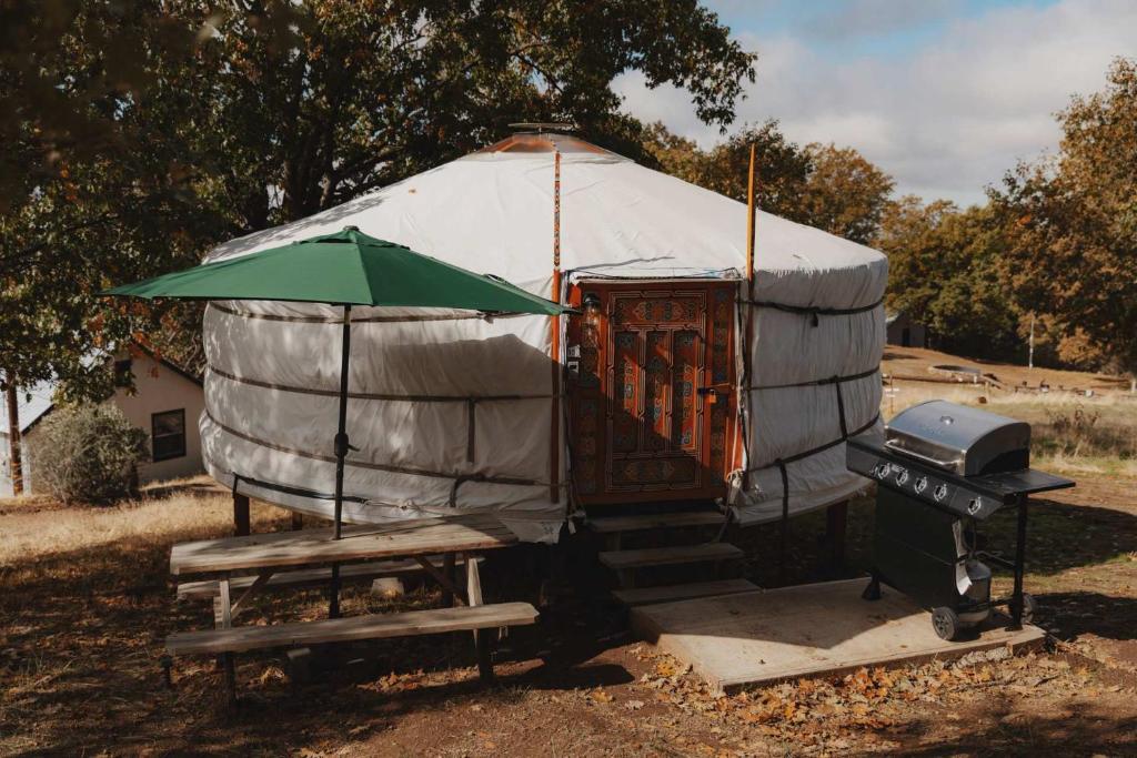 a yurt with a grill and a green umbrella at Glamping yurt at a nature retreat Sequoia Highland in Miramonte