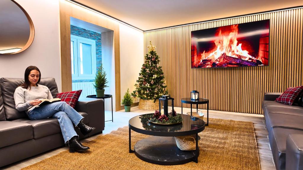 een vrouw op een bank in een woonkamer met een kerstboom bij Hotel Catanies in Pas de la Casa