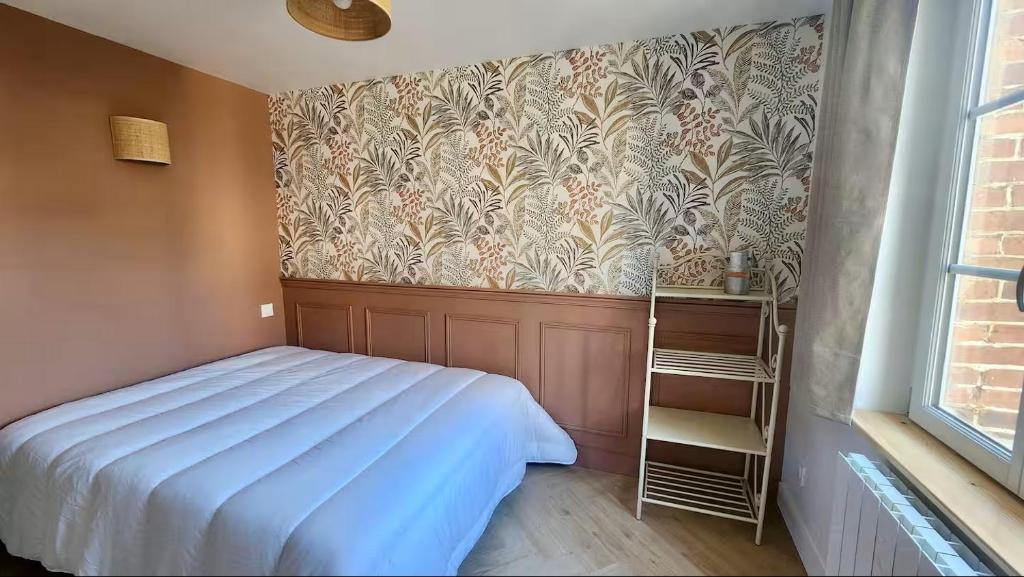 Les Roses - Appartement cosy proche plage - Veules-les-Roses في فول-لي-روز: غرفة نوم بسرير وجدار بورق جدران