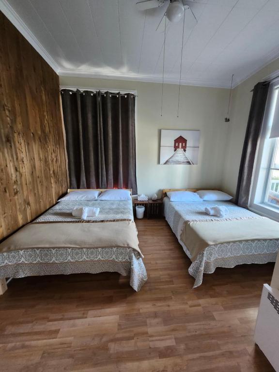 una camera da letto con due letti e una finestra di Auberge du vieux pont a Saint-Raymond