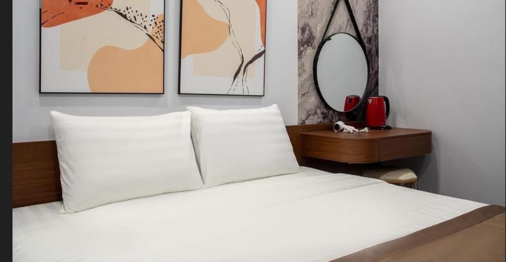 Un dormitorio con una cama blanca con tres cuadros en la pared. en Kapás Hotel, en Hai Phong
