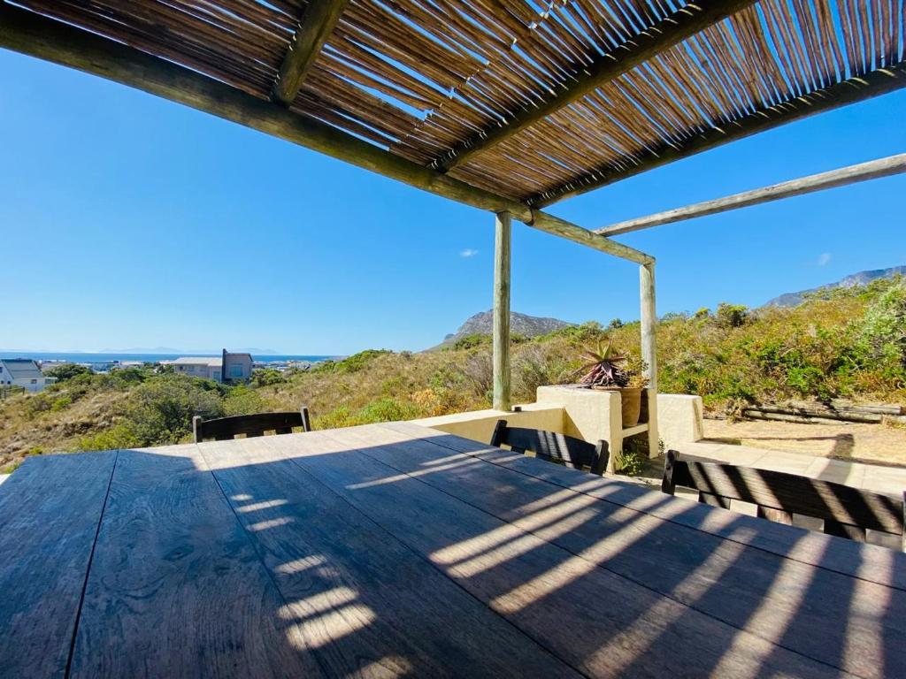 a large wooden table with chairs and a roof at Cape Holly Beach House in Pringle Bay