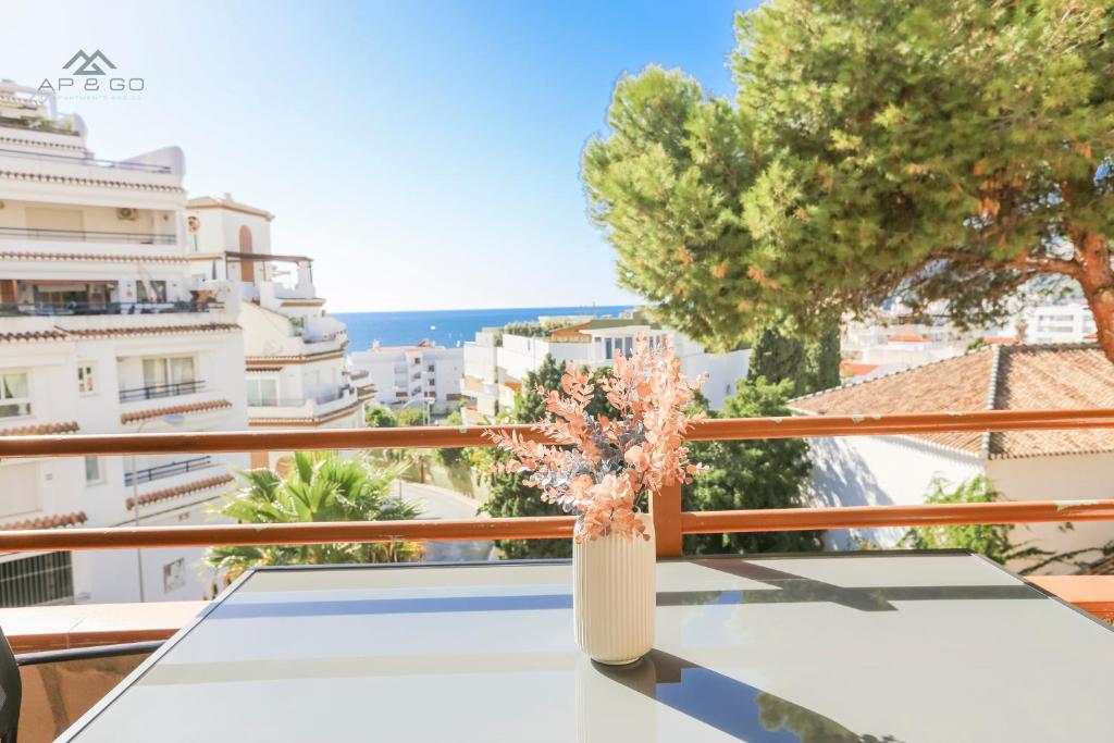 eine Vase mit Blumen auf einem Tisch auf einem Balkon in der Unterkunft Horizon Sea Views and Garage in La Herradura