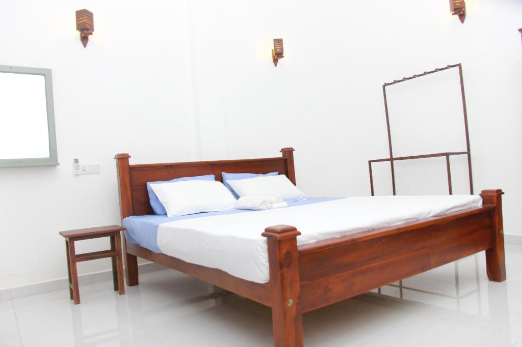 a bedroom with a wooden bed with two pillows at Villa Shiny Aura - Hikkaduwa in Hikkaduwa