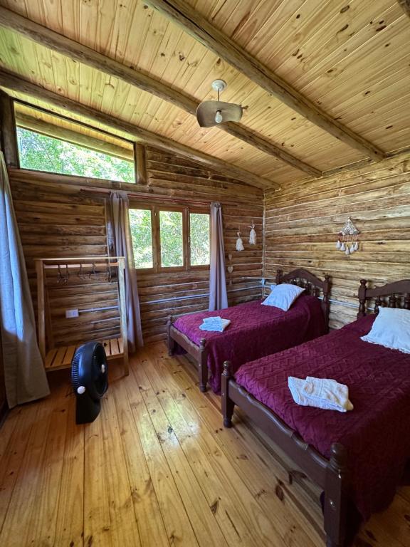 ein Schlafzimmer mit zwei Betten in einer Blockhütte in der Unterkunft La retama in Alta Gracia