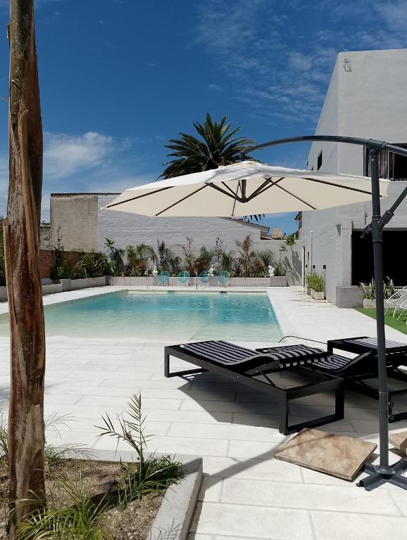 een zwembad met een parasol, een bank en een tafel bij Hotel Marciala in Villa Carlos Paz