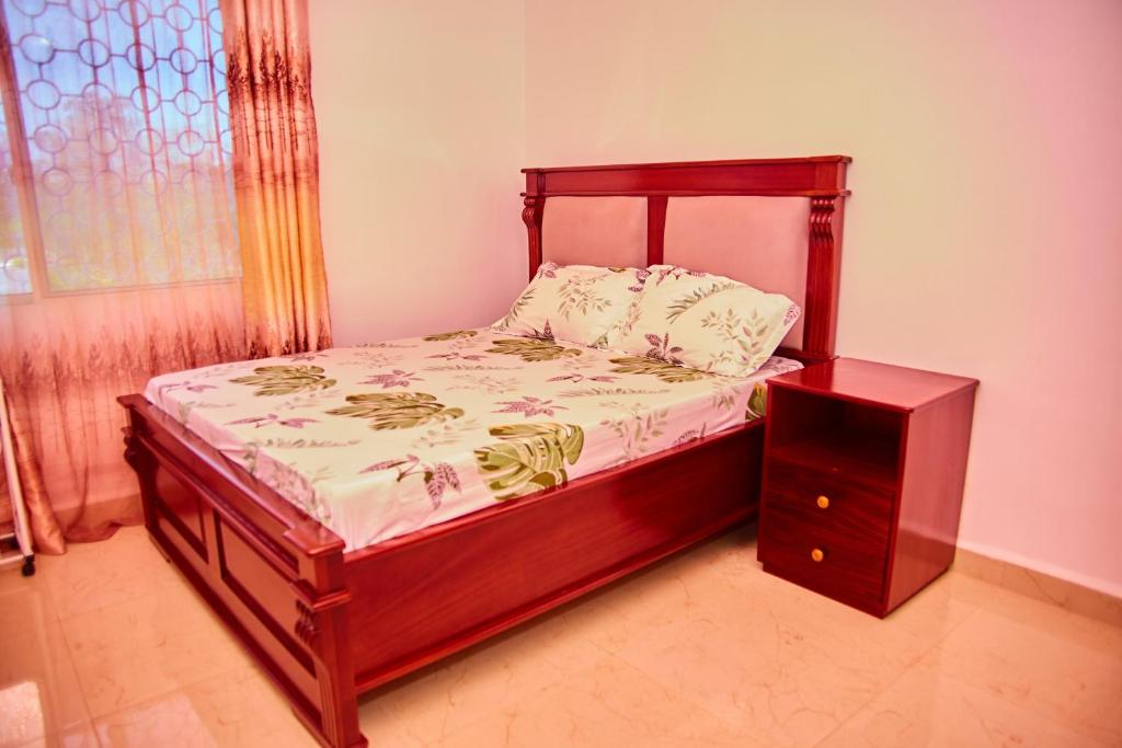 Kilimani Apartment 2 في مدينة زنجبار: سرير بإطار خشبي وموقف ليلي