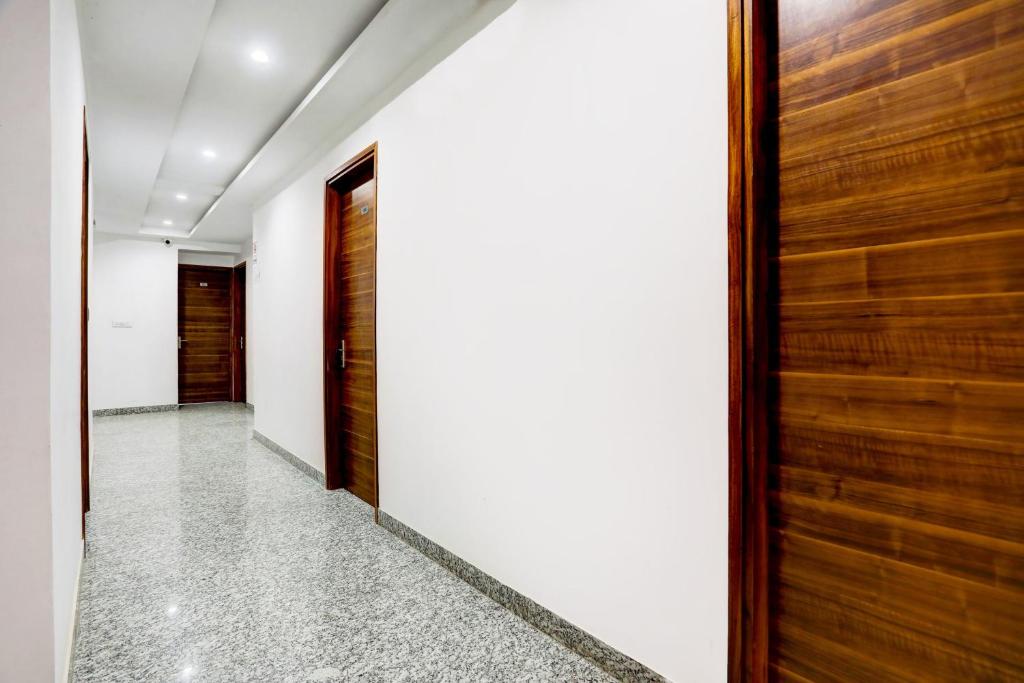 a hallway with a wooden door and white walls at Hotel O Neu-Nest in Rishīkesh