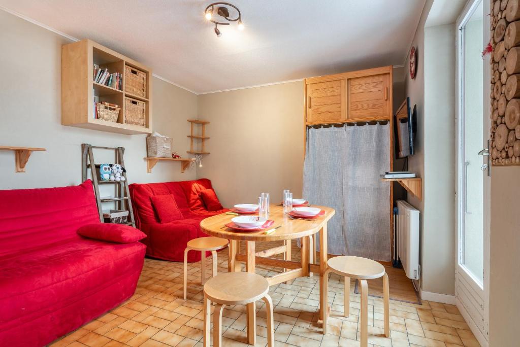 a living room with a red couch and a table at Studio Chaleureux, Plein Sud in Villard-de-Lans