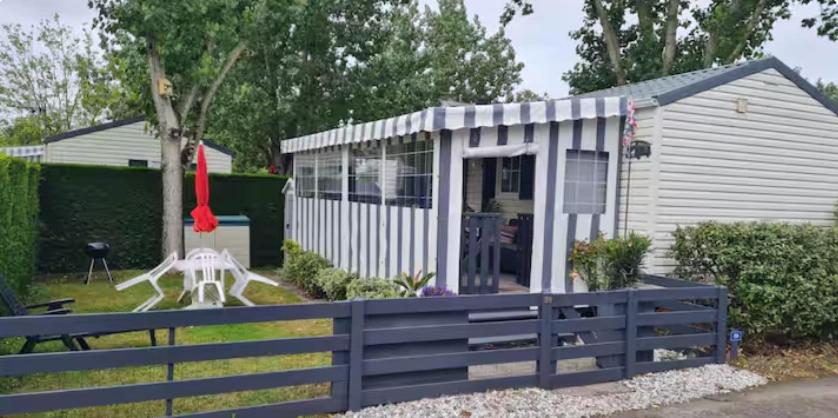 a small white shed with a fence in a yard at La casa du clos in La Bernerie-en-Retz
