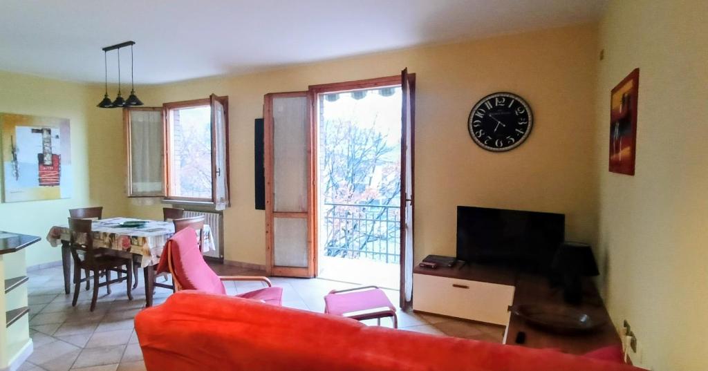 a living room with a red couch and a clock on the wall at Appartamento a Castellarano Manzoni house in Castellarano