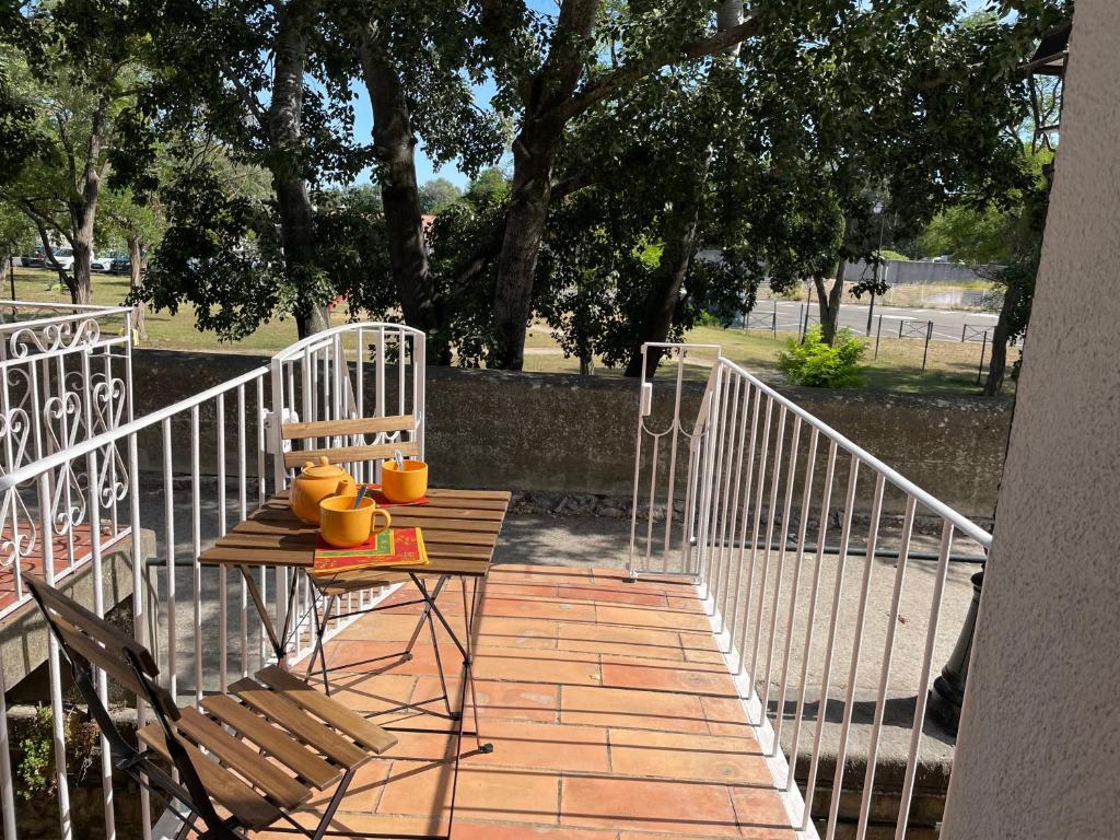 Una mesa y sillas en una pasarela con valla. en Quai n16 - Lieu atypique pour un séjour au calme, en Aramon