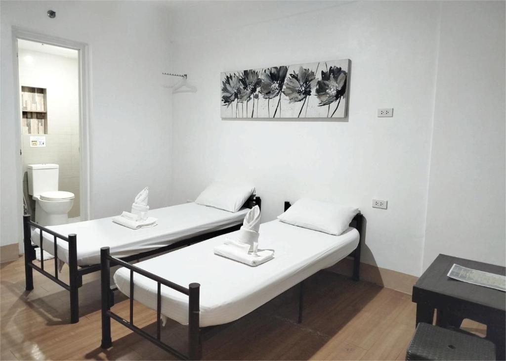 duas camas num quarto com uma mesa e uma foto em Sulit Budget Hotel VMapa em Manilla