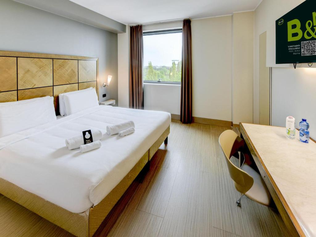 a hotel room with a large bed and a desk at B&B HOTEL Padova in Padova