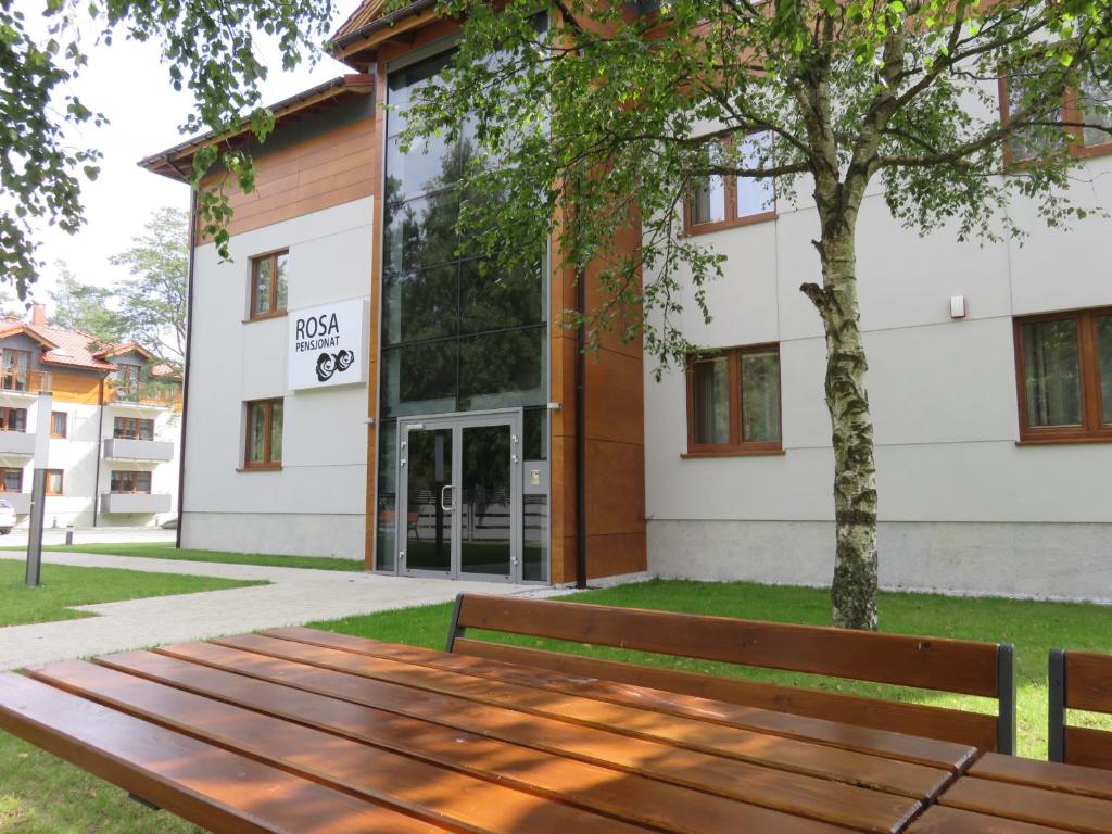 a wooden bench in front of a building at Rosa Apartamenty in Dąbki