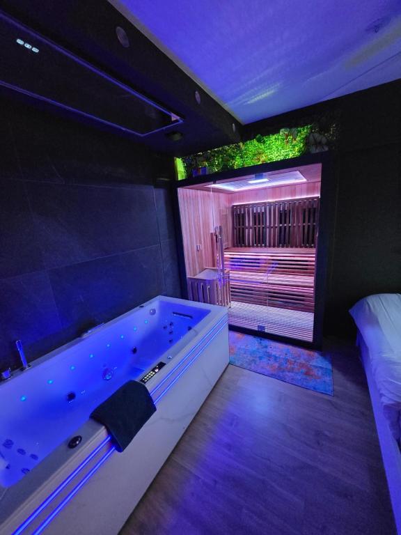 T2 Cosy spacieux Balneo Sauna Parking Noel في ستراسبورغ: حمام كبير مع حوض استحمام مع إضاءة أرجوانية