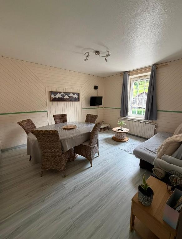 Appartement La Vanne Confortable et équipé في لابريس: غرفة معيشة مع طاولة وكراسي وأريكة