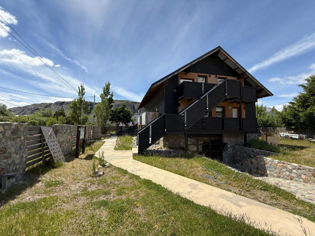 a house with a black facade on a hill at Campo Base Aparts in El Chalten