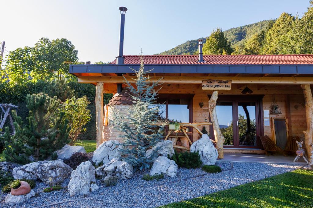 a log cabin with rocks in front of it at Lake Cottage - Koča ob jezeru in Nazarje