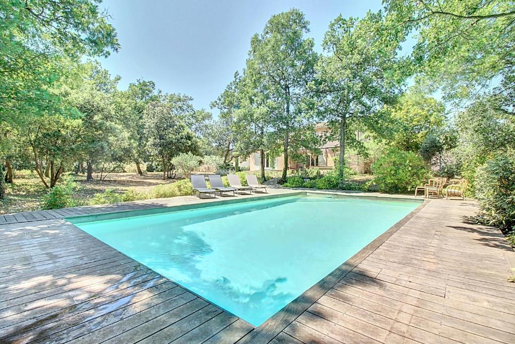 een zwembad in een achtertuin met een houten terras bij La maison Calavoun in Maubec